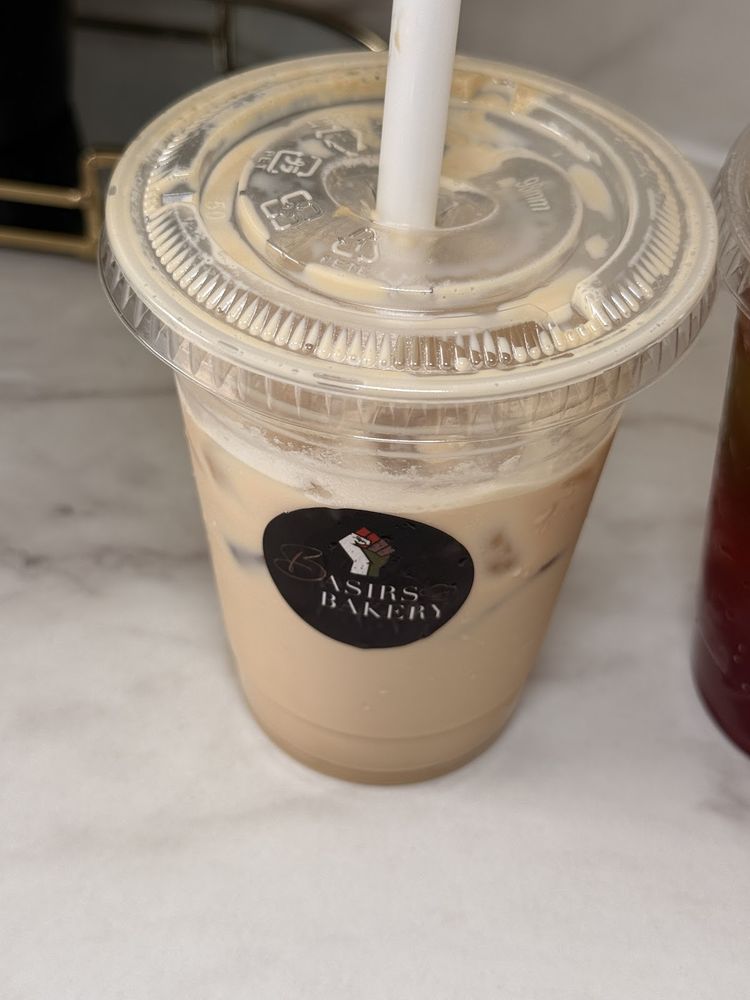 An iced coffee in a clear cup with a straw on a marble counter