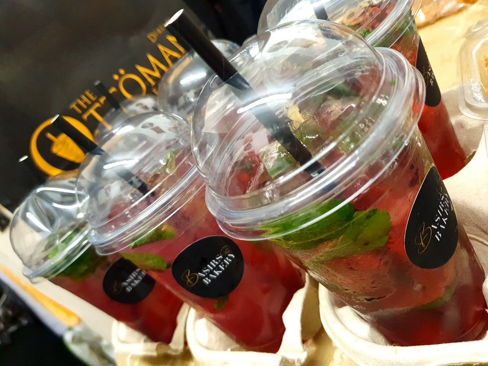 Two lidded cups of red fruit-and-mint mocktail close on the counter under warm light